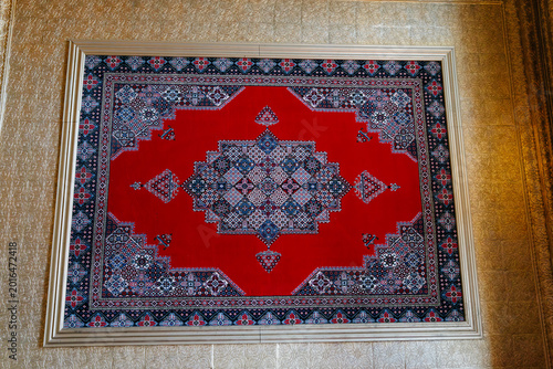 Cuadro en lienzo Framed traditional Kyrgyz carpet with red geometric ornament hanging on textured