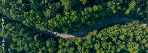 Top view road in beautiful autumn forest at sunset, trees with red and orange leaves , Beautiful landscape view from flying drone in Nature