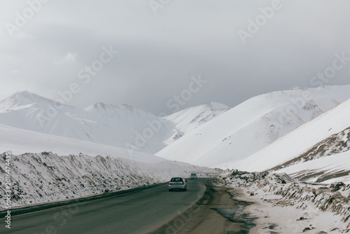 Foto Scenic winter highway crossing Ala-Bel Pass in Kyrgyzstan, with cars driving thr
