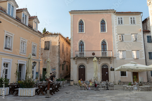 Canvastavla Sunlit view of a quiet stone square with pastel facades, shuttered windows, and