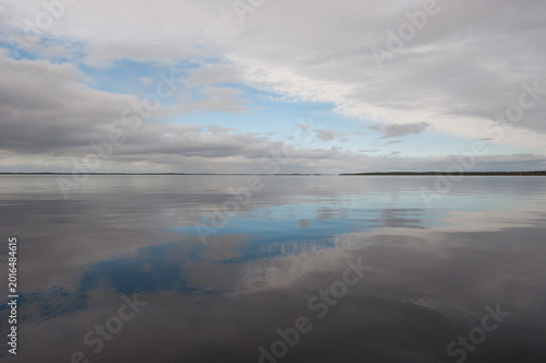 Clouds reflected on the calm surface of the lake Inari in Lapland, Finland in summer