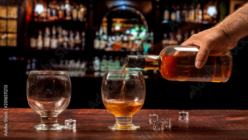 Cuadro en lienzo Hand pouring whiskey into glass at Irish pub bar