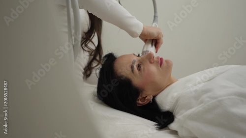 Relaxed woman receiving modern microneedle rf -lifting facial procedure from professional cosmetologist. Innovative technology for skin tightening, wrinkle reduction, collagen stimulation.