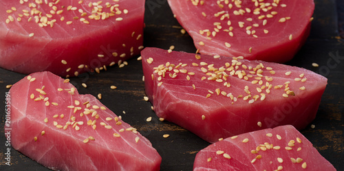 Raw tuna pieces in sesame seeds on a cutting board