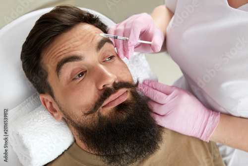 Bild auf Leinwand Closeup of bearded man getting beauty injection at aesthetic clinic