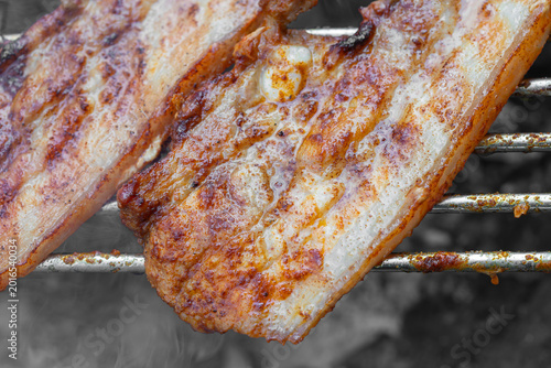 Grilled pork belly cooking on an outdoor barbecue grill
