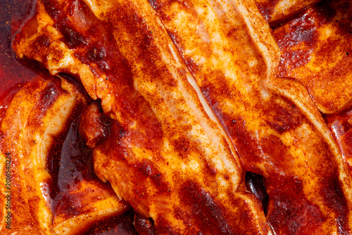 Raw pork belly marinating with bold barbecue rub spices