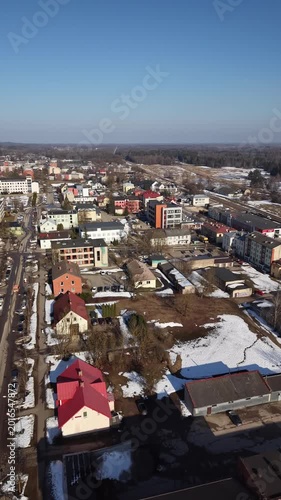 Aerial view of a snowy town with colorful buildings, roads, and clear blue sky showcasing urban landscape in winter