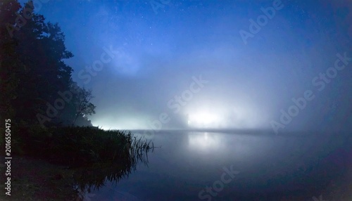 Misty lake scene with a tranquil water surface and dark silhouettes