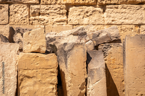 Weathered stone blocks with rough textured surfaces, natural sandstone background featuring layered rock patterns, traditional Maltese limestone masonry and building material abstract close-up.