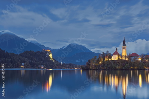 Bild auf Leinwand Bluish sunset over the castle and the Assumption of Mary church on Bled island, seen eastward from Kidriceva cesta across Lake Bled
