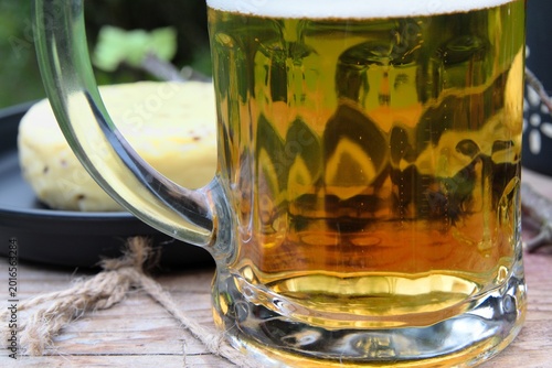 Tableau sur toile Close-up of a mug of lager beer, traditional caraway cheese on a black tray in t