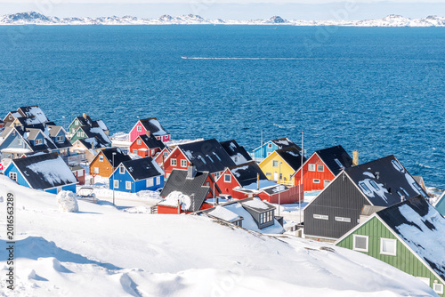 Dense greenlandic capital residential suburb with colorful Inuit houses, snow covered rooftops and arctic fjord shoreline, Nuuk, Sermersooq, Greenland