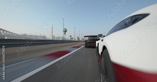 Race cars driving side by side on a racetrack during daytime, close view with motion blur emphasizing speed, clear sky and track details visible