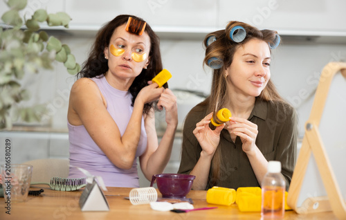 Tableau sur toile Adult woman and young woman doing hair perm on curlers