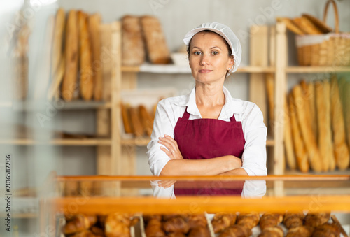 Valokuva Portrait of professional positive female baker in uniform in bakery