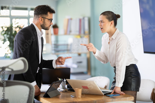 Tableau sur toile Young male and female standing on opposite sides of table and shouting at each other