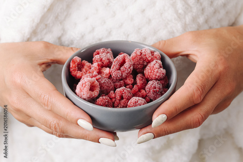 Fotografía Woman holding bowl with frozen raspberries