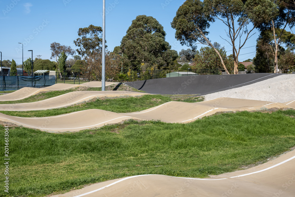 Naklejka premium A modern BMX pump track and bicycle skills course at a suburban sports facility in Sunbury Melbourne, Australia, featuring smooth and compacted sand berms, rollers and undulating track surfaces