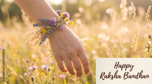 Hand wearing floral nature rakhi bracelet made of lavender wheat and wildflower in golden meadow