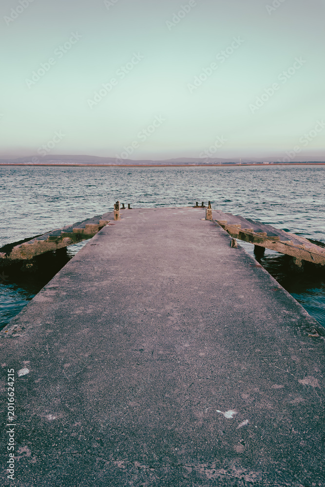 Obraz premium Concrete Pier Extending into the Calm Waters of Cais do Abrigo in Torreira Portugal