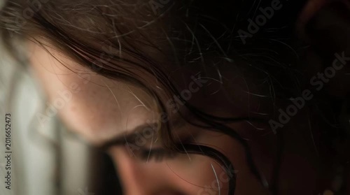 Close up of woman face looking through window while crying in moment of sadness and deep emotion