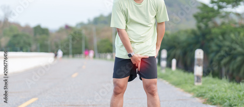 Foto Young adult male runner suffering from acute groin pull and muscle pain during running workout