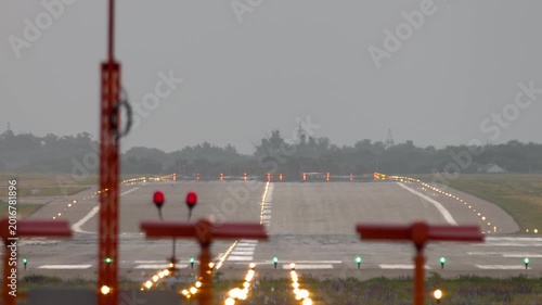 End view of an empty airport runway illuminated with landing lights. Aviation scene perfect for travel, transportation, and airport themes