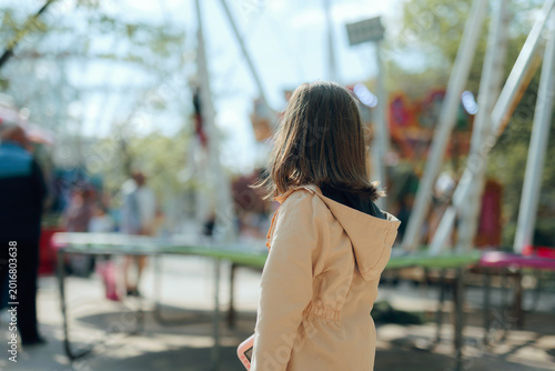 Schilderij op canvas Girl Wearing Beige Trench-coat Looking At Trampoline in Amusement Park