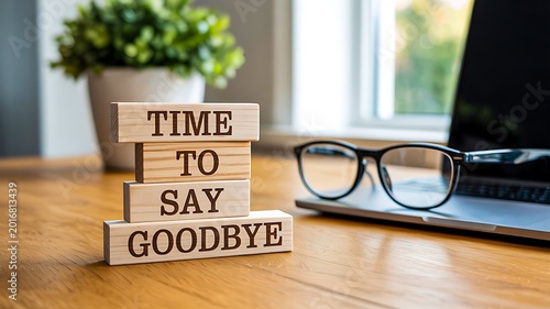 Time to say goodbye message on wooden blocks with glasses on desk in bright office setting