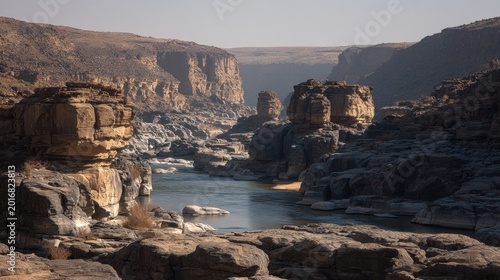 Majestic river carving through ancient stratified rock formations in a vast, arid canyon landscape