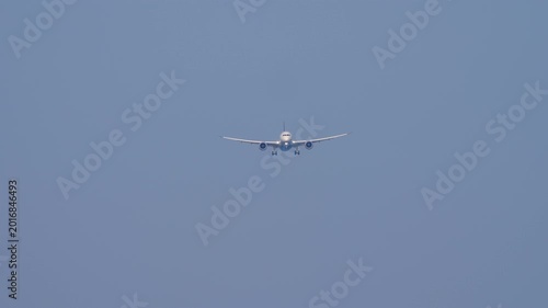 Jet wide body airplane with an unrecognizable livery approaching landing, front view, long shot