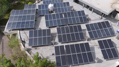An aerial view of a modern rooftop solar power system installed on a large building. Multiple photovoltaic solar panels are arranged efficiently across the rooftop to generate clean, renewable energy.