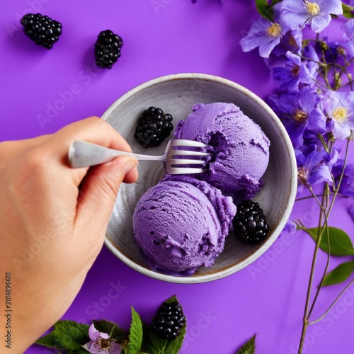Scooping Purple Ice Cream in a Bowl With Blackberries and Flowers on a Purple...