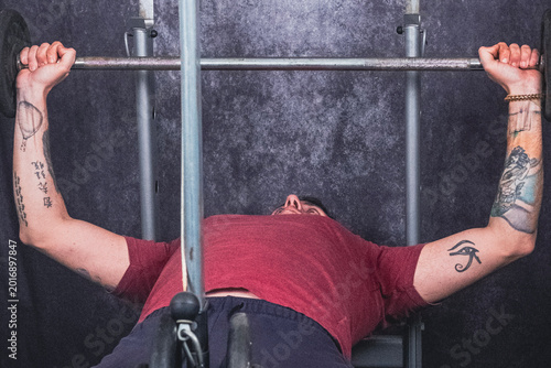 Schilderij op canvas A man lifts a barbell while on a bench to work his pectoral muscles