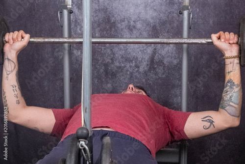 Schilderij op canvas A man lifts a barbell while on a bench to work his pectoral muscles