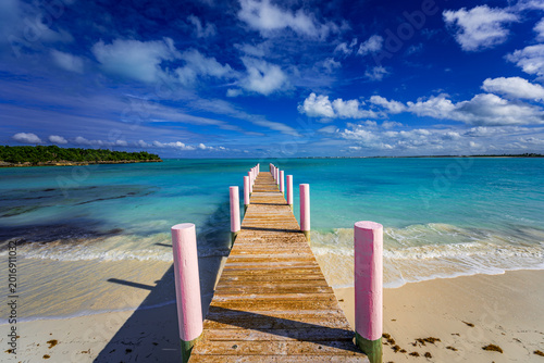 Bild auf Leinwand Wooden pier with pink posts leading into crystal-clear turquoise water at Casuar