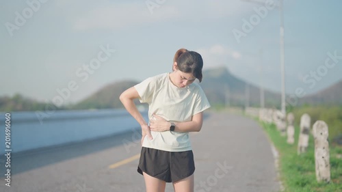 Adult runner suffering from side stitch and waist pain during exercise. woman holding his side due to sharp abdominal cramp or muscle ache while running. Sports injury and healthcare concept
