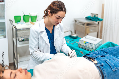 Minor surgery. Medical procedure, Surgeon at work, Healthcare and Medicine concept. Professional female doctor in white coat performing a precise dermatological surgical procedure on a patient.