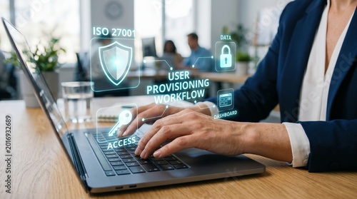 Business professional using laptop with holographic security icons. ISO 27001 compliance, user provisioning workflow, and data protection concept.