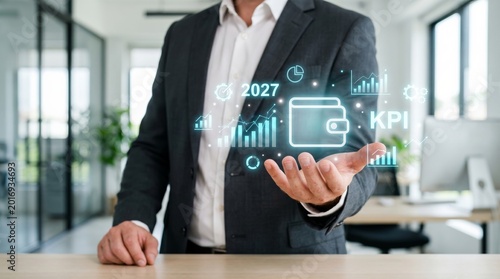 Businessman holding hologram with financial analytics icons, wallet, and 2027 forecast. Business growth, KPI metrics, and digital financial planning concept.