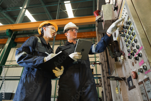 Engineer man and woman worker working with tablet computer and checking machine in warehouse for production supply