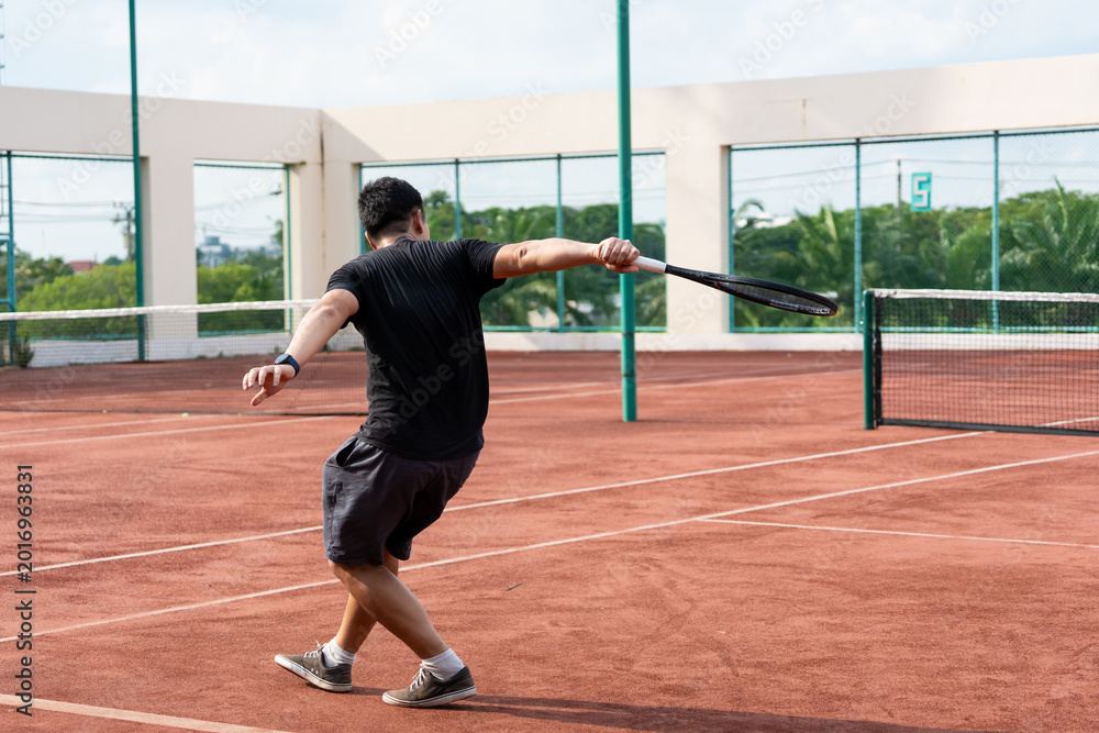 Fototapeta premium Asian young sportsman exercise, playing tennis on outdoor clay court.