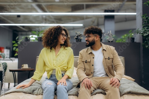 Happy couple shopping choosing new bed in furniture store