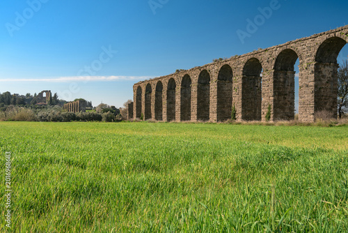 Aspendos Ancient Roman aqueduct ruins in green spring meadow