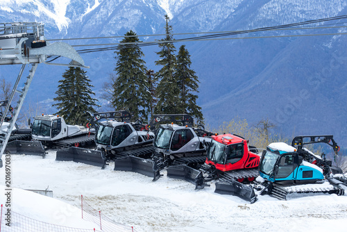 Bild auf Leinwand Several snowcats in a picturesque ski resort against the backdrop of beautiful m