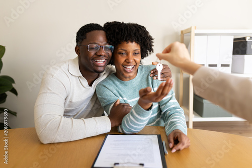 Happy couple receiving keys from real estate agent after signing a contract