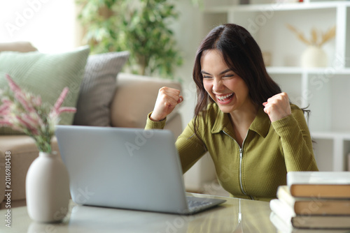 Excited young woman checking good news on personal computer