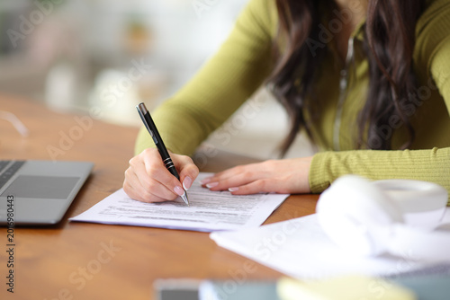 Obraz na plátně Student hands filling out form on a wooden table