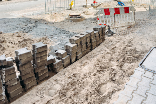 Quadro su tela Stacks of interlocking stones sit on sand at construction site